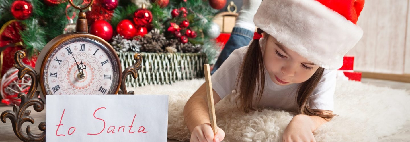 Pretty girl in Santa hat writes letter to Santa